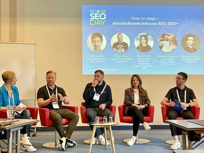 Five people are sitting on a stage discussing Inhouse SEO.