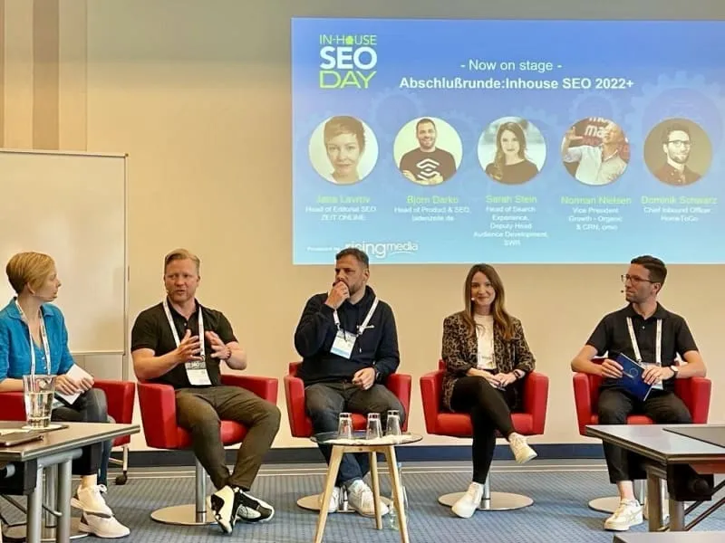 Five people are sitting on a stage discussing Inhouse SEO.
